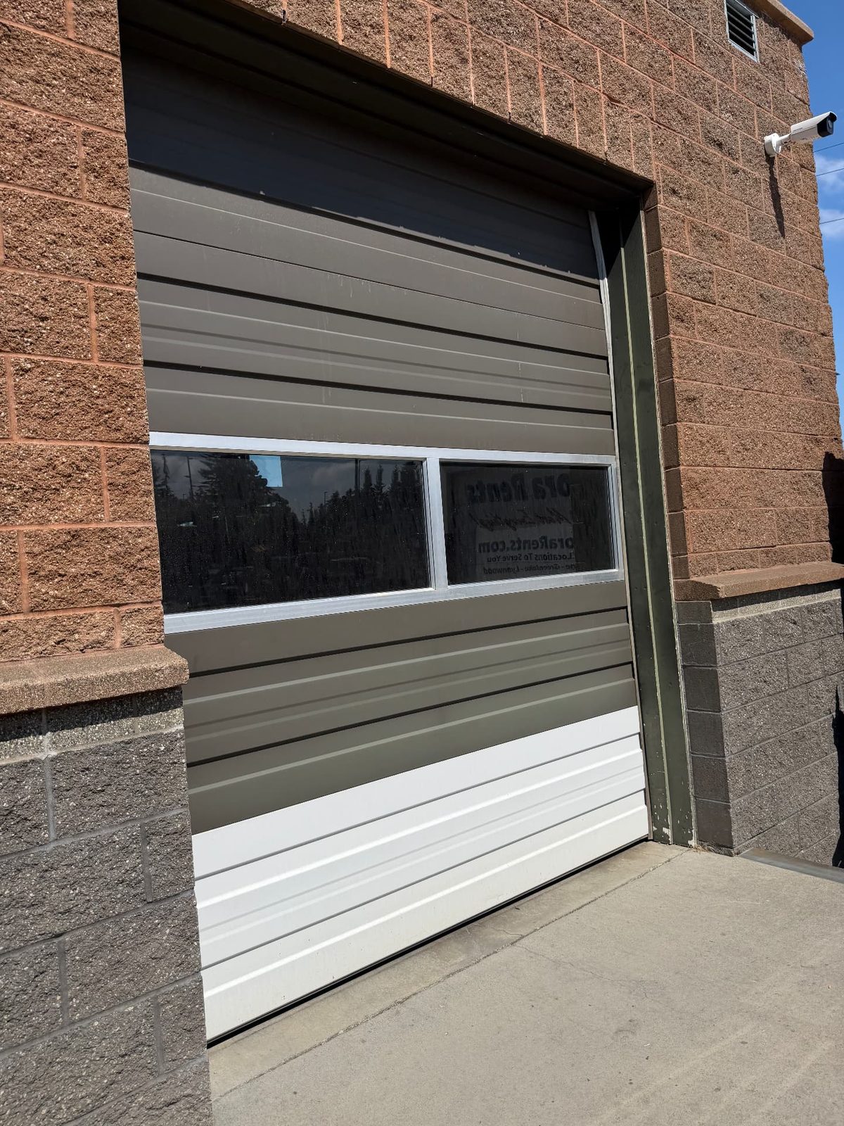 Close view of the repainted overhead commercial garage door with window panels at the Aurora Rents property in Shoreline